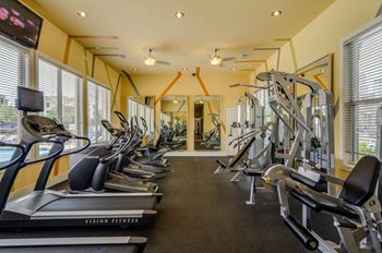 Fully equipped fitness Center with large windows providing view of pool area at Ashley Auburn Pointe in Atlanta, GA
